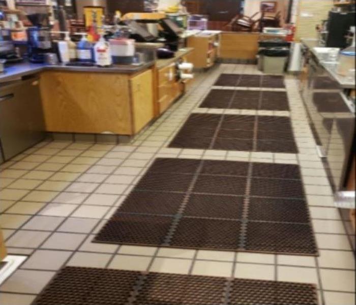 A restaurant kitchen nice and clean with brown rubber floor mats. Brown kitchen cabinets with kitchen essentials.
