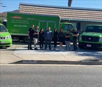 Group picture of the SERVPRO Team next to their green work trucks. 
