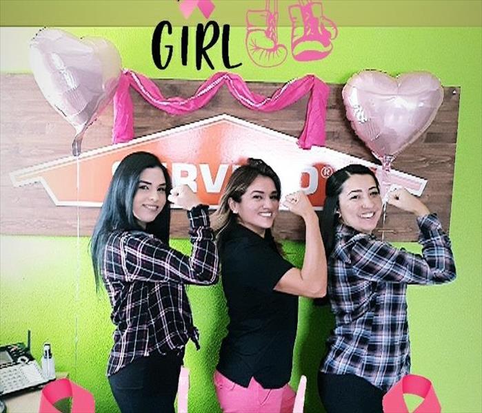 Our office girls flexing their right arm. Happy with balloons and pink banners surrounding them.